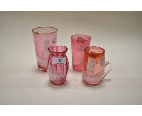 Four late 19th century cranberry glass wares, overlaid in the Mary Gregory style, including two beakers depicting girls and f