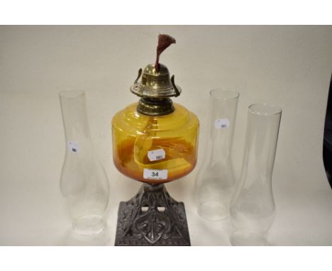 A late 19th/early 20th century oil lamp, having cast metal base with anchor design, amber glass reservoir and three clear gla
