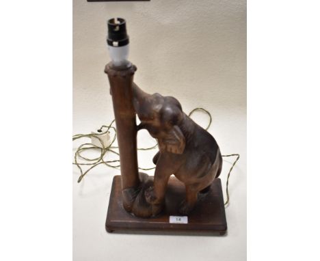 A Mid century Burmese carved lamp having elephant with his trunk wrapped around a tree trunk.