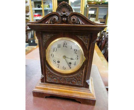 Early 20th Century carved walnut mantel clock, the silvered dial with Arabic numerals, the two train movement striking on a g