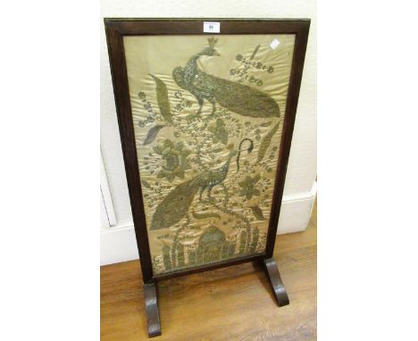Early 20th Century oak firescreen inset with an Indian silk, metal thread and sequin picture of peacocks and flowers, 78cms x