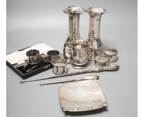 A pair of silver posy vases, a silver mug, a silver dish, five silver napkin rings, two button hooks and a cased silver pushe