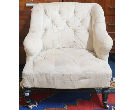 A 19th century button back upholstered armchair in the manner of Howard and Sons with shaped back and arms on ebonised turned