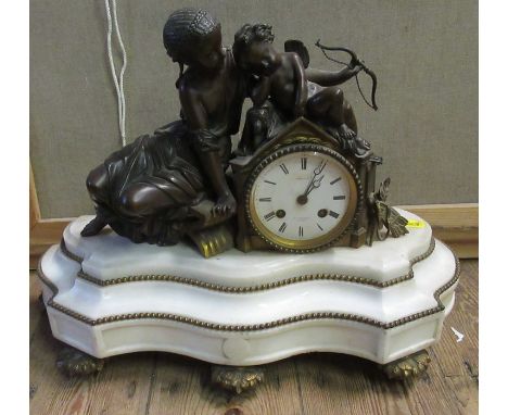 A continental mantel clock, the chiming movement with circular white enamel dial surmounted by figures, raised on a shaped ma