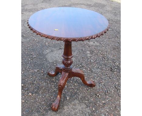 A mahogany tripod table, with carved edge, raised on a bird cage to a carved column and three outwept supports, diameter 23in