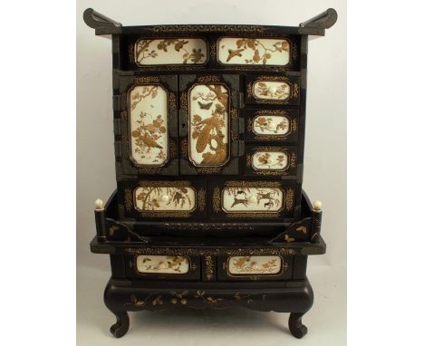 An early 20th century Japanese lacquered Shibayama table cabinet, fitted with an assortment of drawers and cupboards revealin