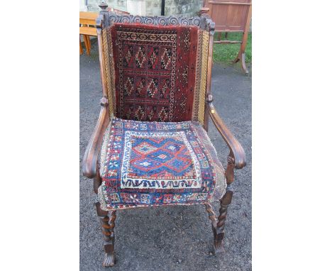 An oak framed bergere armchair, with carved top rail, raised on barley twist front supports and stretcher, with carpet panel 