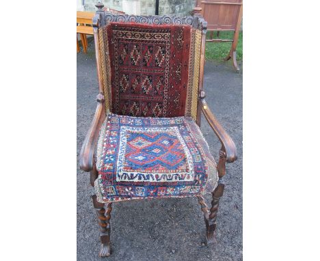 An oak framed bergere armchair, with carved top rail, raised on barley twist front supports and stretcher, with carpet panel 