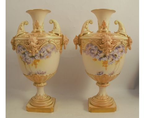 A pair of Royal Worcester blush ivory vases, decorated with flowers and blue trailing flowers, with mask handles and rings, d