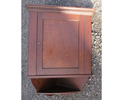 An oak corner cupboard, with dentil cornice over the single panel door, fitted with a shelf below, height 34ins, width 24ins