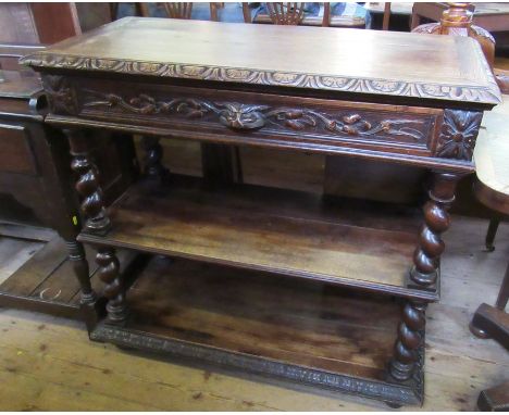 An oak three tier oak buffet, with carved decoration, fitted with one long drawer over shelves with barley twist supports, wi