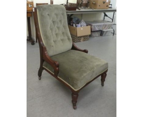 An Edwardian mahogany showwood framed nursing chair, later part button upholstered in green fabric, raised on ring turned for