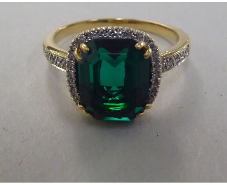 A yellow metal claw set ring with synthetic emeralds and diamond shoulders&nbsp; stamped 750 