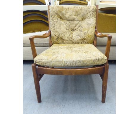 A vintage Parker Knoll, stained beech framed fireside armchair, raised on turned legs and stretchers 