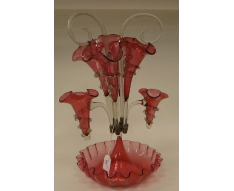 An Edwardian Cranberry glass epergne with frilled borders, comprising a series of six trumpets and crook stems, set in a shal