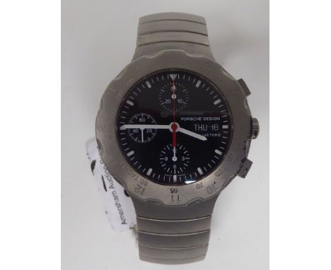 A Porsche Design titanium cased bracelet chronograph, faced by a black baton dial with a rotating bezel, three subsidiaries a