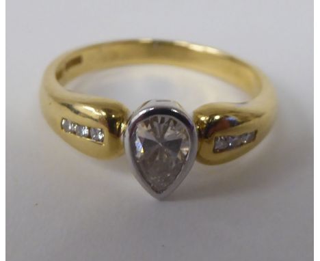 A gold coloured metal ring, set with a single stone, pear shaped diamond, between diamond shoulders&nbsp; stamped 750 