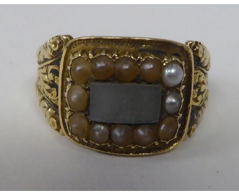 An antique gold coloured metal mourning ring with an engraved shank, set with seed pearls&nbsp; 