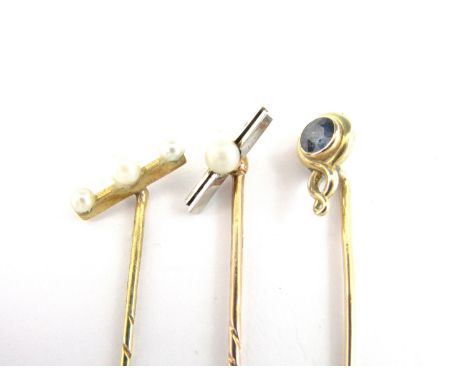 Three early 20th Century yellow metal stick pins, two set with a bar and seed pearls to the terminal, the third set with a bl