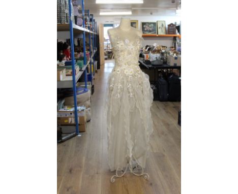 Female mannequin on turned metal stand with floral flowing dress  