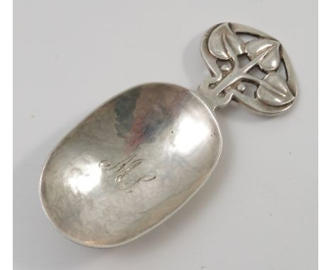An A E Jones silver caddy spoon, the pierced handle decorated with three leaves to an oval bowl engraved with initials, Birmi