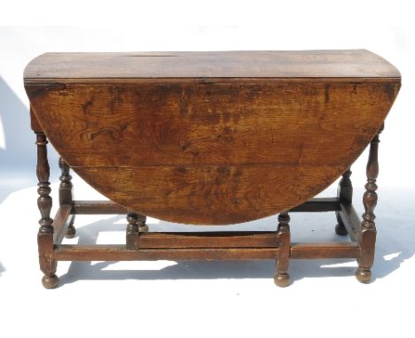 An Antique oak oval gate leg dining table, fitted with an end drawer, raised on turned legs, 57ins x 51ins 