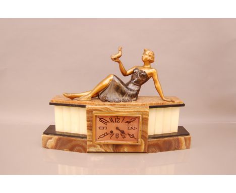 An Art Deco French mantle clock, 55cm wide, in marble surmounted by an elegant lady holding an exotic bird, tail snapped off,