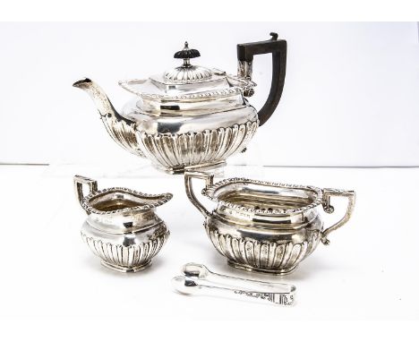 An Edwardian silver three piece bachelor tea set by W.A, half fluted with egg and dart rims, comprising teapot, sugar basin a