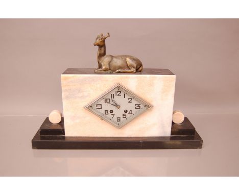 An Art Deco French mantle clock, 46cm wide, with black hardstone and applied plank hardstone, surmounted with a small spelter