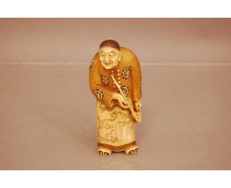 A Japanese late Meiji period carved ivory figure of an elder, 14cm, with red lacquer panel to underside with signature, well 