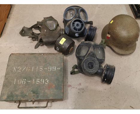 3 military gas masks; a military ammunition box; a WWII German helmet 