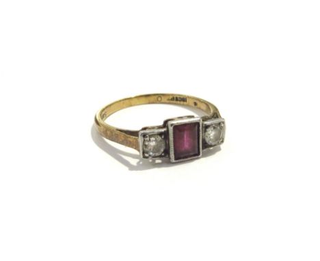 An 18ct gold ring centrally set with an emerald cut ruby flanked by diamonds in square mounts. Size N, 2.4g