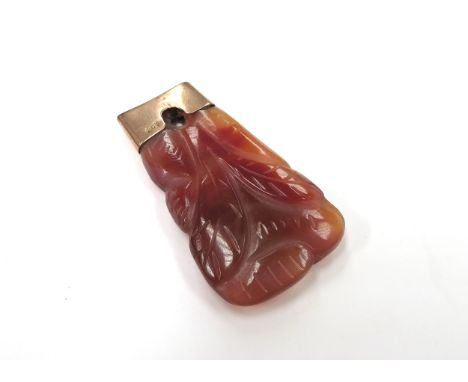 A carved red jade pendant with a rose gold mount stamped 9ct, 4.8cm long