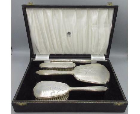 20th century silver mounted cased vanity set to include three brushes and a comb decorated with engine turned pattern and eng