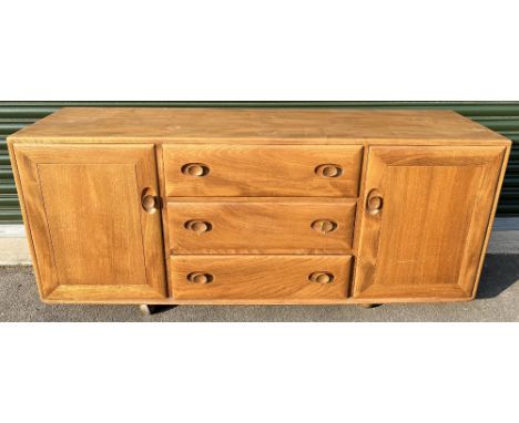 Ercol light/natural finish sideboard, model 455, fitted with three long drawers flanked by cupboards, on rollerball castors, 