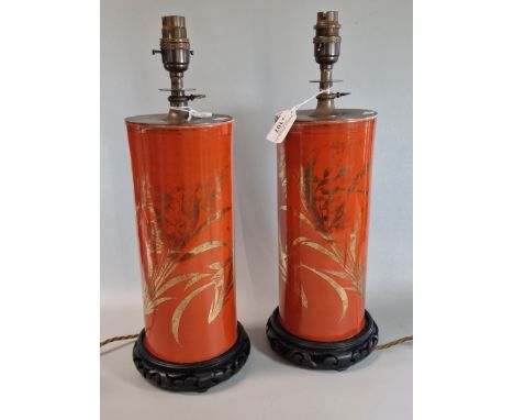 Pair of ceramic orange ground cylindrical lamp bases, in Japanese style, with gilt flowers, both on carved wooden bases. Exte