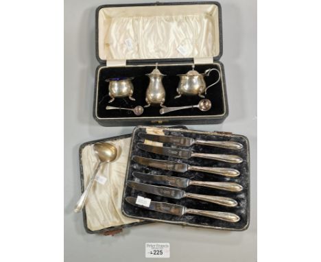 A cased silver condiment set with one silver and one silver-plated spoon together with a cased set of silver handled butter k