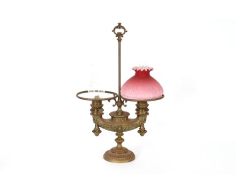 A brass double burner Wild Wessell table oil lamp, having single cranberry tinted shade, central loop handle, 65cm high x 42c