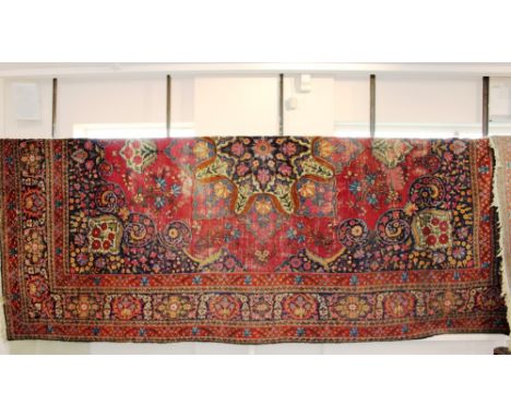 A Tabriz pattern carpet, having central medallion on a magenta coloured ground, dark blue spandrels, border with guards, (wor