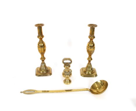 A pair of tall brass candlesticks, with knopped stems and square bases, 29cm high; two brass bell weights and a brass ladle, 