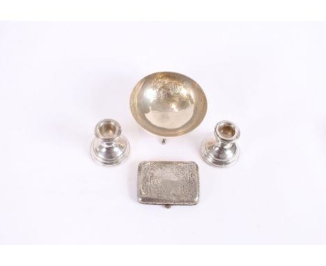 An Edwardian silver foliate engraved cigarette case; a pair of modern silver dwarf candlesticks; and a continental white meta