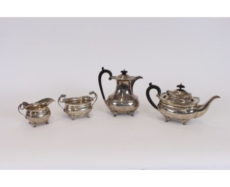 A George V four piece silver teaset, having canted corners with floral embossed motifs, raised on paw supports and initialed 