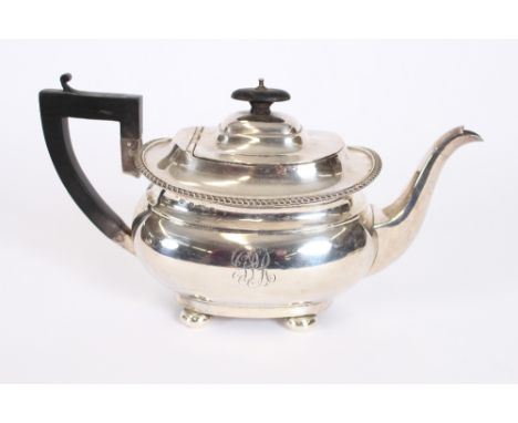 A George V silver teapot, having gadrooned border raised on four bun feet, black wood handle and lift, monogrammed, Birmingha