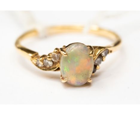 An opal and diamond ring, comprising an oval opal with cross over diamond set shoulders, three diamonds either side, size R, 