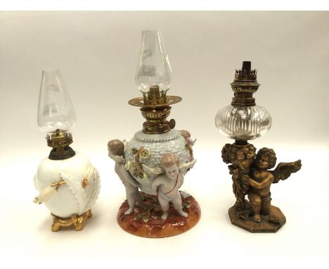 A ceramic oil lamp with three cherubs supporting reservoir; together with a ceramic oil lamp decorated with flowers and gildi