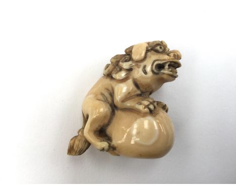  A Japanese Meiji period carved ivory netsuke of Karashishi, the lion dog seated upon a ball, signed to base. Height 3.4 cm.