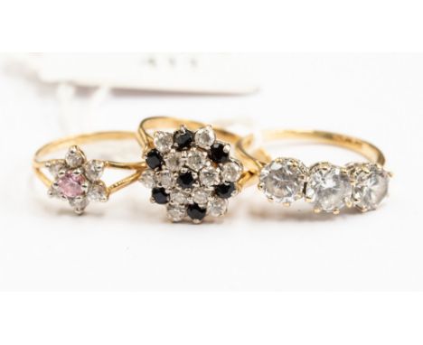 Three 9ct gold cubic zirconia set dress rings, comprising a cluster a three stone ring and a flower head ring, sizes N and O 