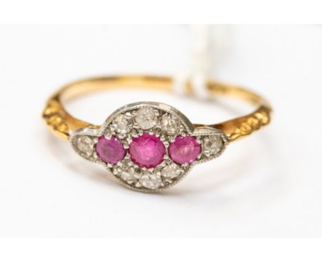 An Edwardian 18ct gold ring, set with three rubies, with a surround of diamond chips, size P, with a total weight of approx 1