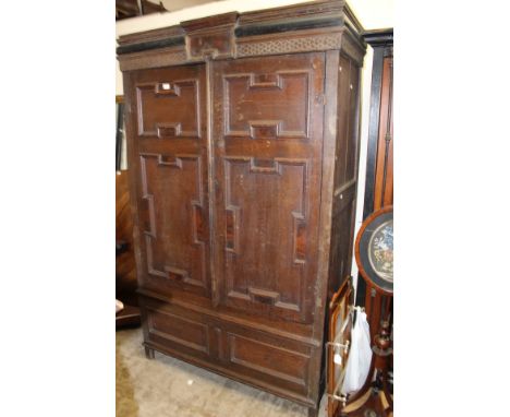 A late 17th Century joined oak cupboard two door cupboard, the cornice with fish scale decoration, the doors with geometrical