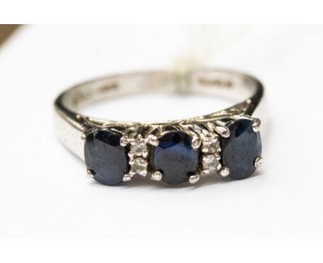 A platinum and sapphire ring set with three oval sapphires, with two small diamonds between each, size O 1/2, with a total gr